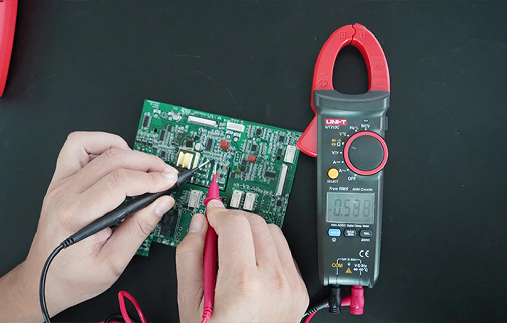 Un clește ampermetric și sonde de testare utilizate pentru a testa componentele de pe o placă de circuit.
