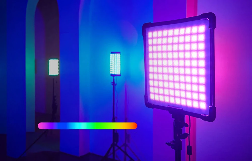 Trei panouri dreptunghiulare cu puncte luminoase colorate, montate pe trepiede, într-o încăpere cu iluminare albastru-violet
