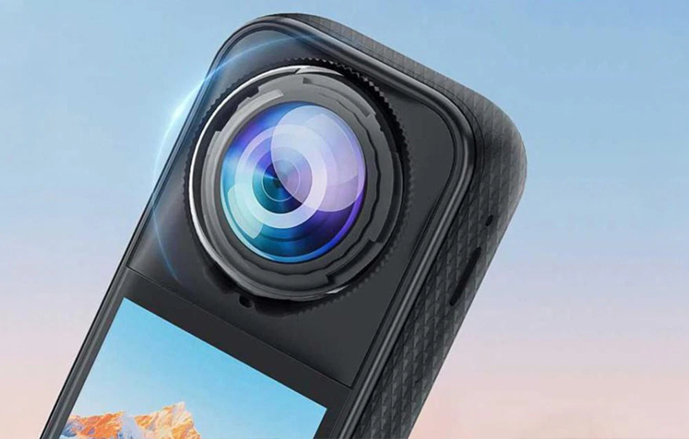 Prim-plan al obiectivului unei camere Insta360 cu un capac de protecție transparent pe fundalul unui cer albastru