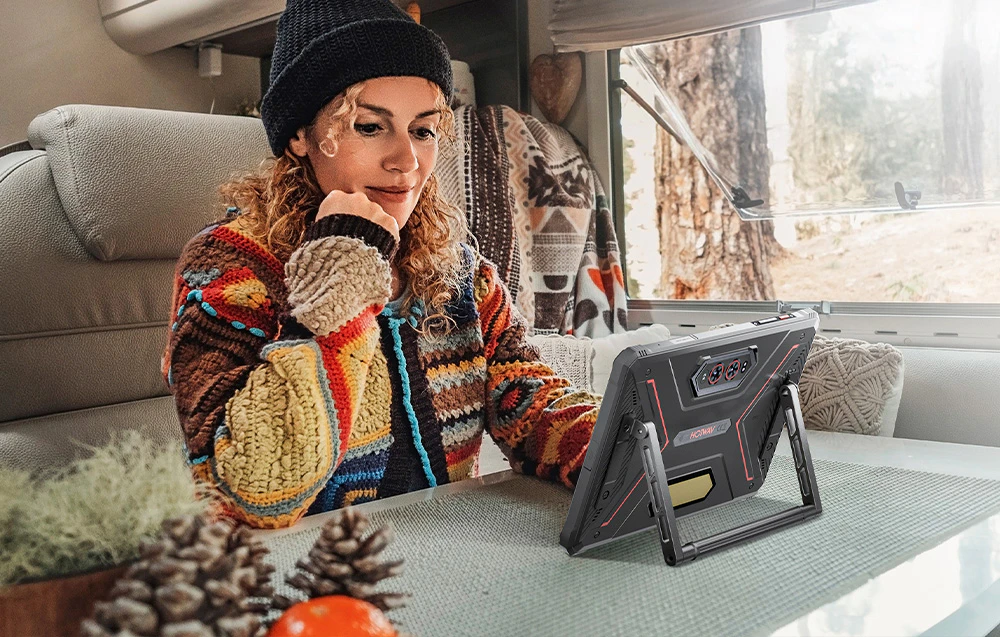 Femeie așezată într-o rulotă de camping folosind o tabletă așezată pe un suport