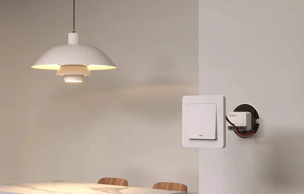 Modul Sonoff instalat într-o cutie încastrată lângă un întrerupător pe peretele din sufragerie