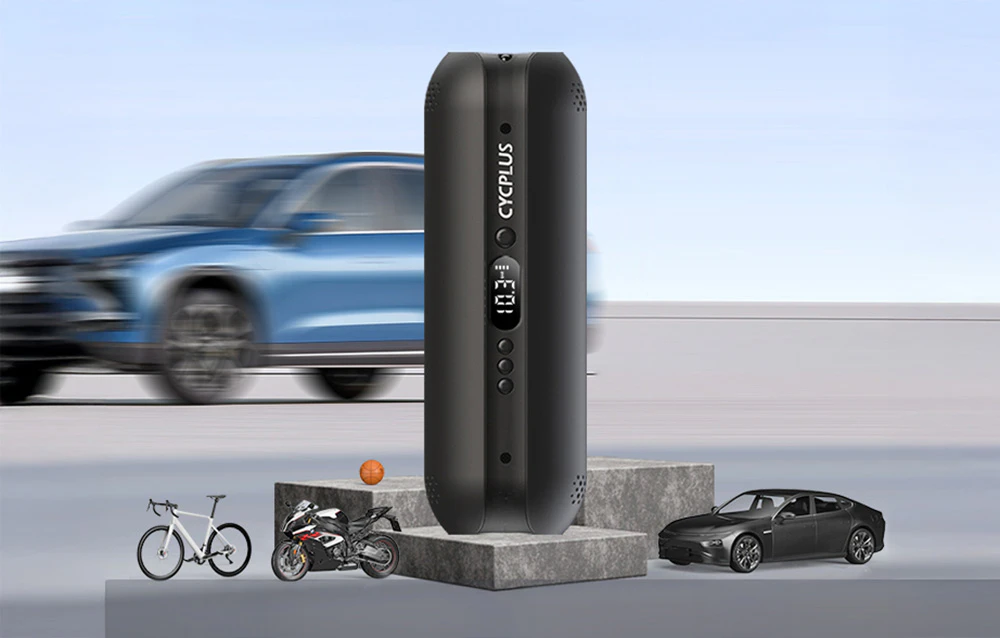 Pompa electrică Cycplus AL1 în poziție verticală pe cuburi de beton cu o mașină pufoasă în fundal