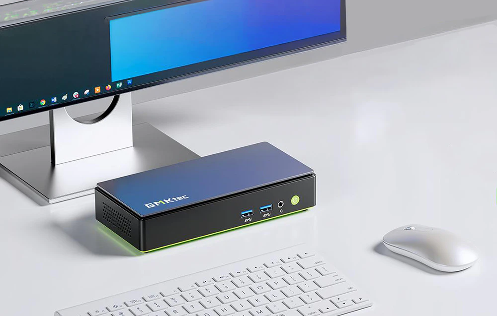 Mini PC-ul GMKtec K13 se află pe un birou lângă un monitor, o tastatură și un mouse într-un spațiu de lucru modern și minimalist.