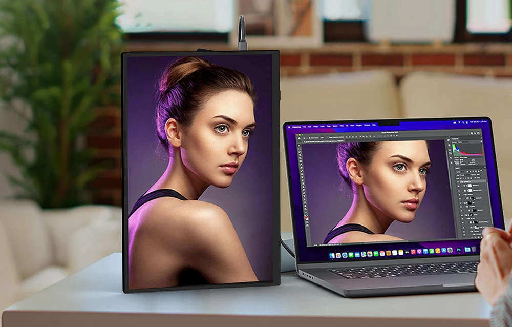 Un monitor portabil poziționat vertical lângă un laptop în timpul editării unei fotografii portret
