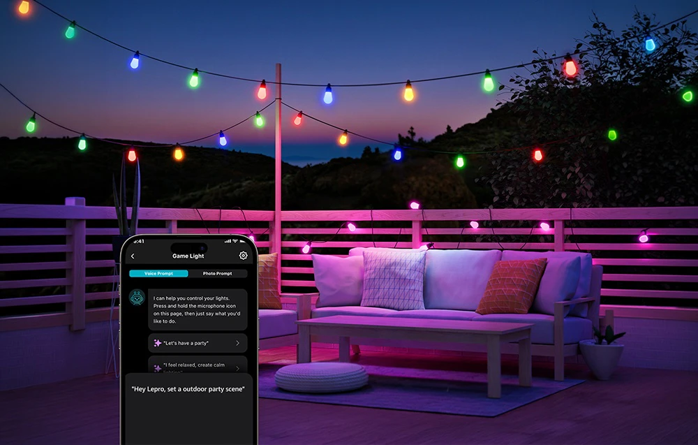 O ghirlandă luminoasă colorată deasupra unei terase cu o canapea; în colțul din stânga jos, ecranul unui smartphone cu funcție de comandă vocală.