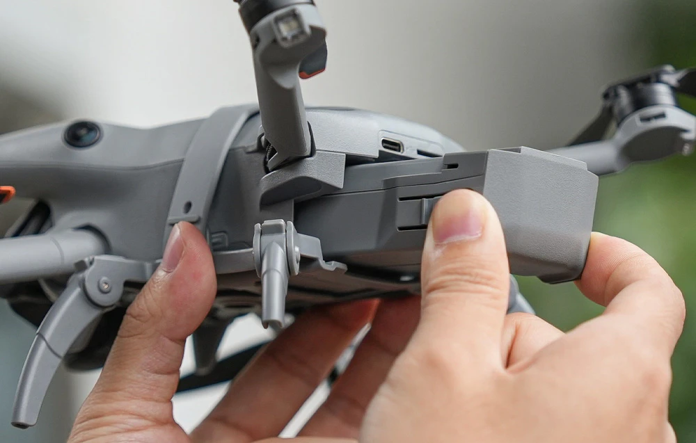 Prim plan al mâinilor care îndepărtează sau introduc bateria în drona DJI Mini 5 Pro
