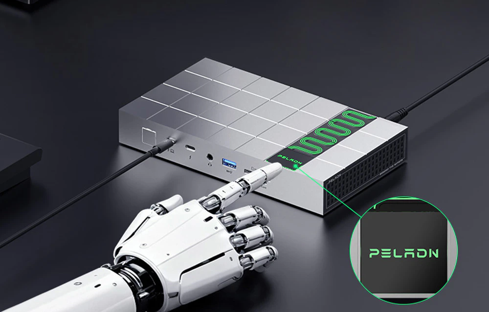 O mână robotică, alb-negru, arată cu degetul spre logo-ul „PELADN” iluminat în verde de pe carcasa stației de andocare gri. O imagine mărită a logo-ului mărcii este prezentată într-un cerc.