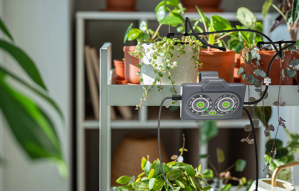 Controler de irigare RainPoint® montat pe un raft alb cu plante în ghivece, prezentând sistemul de tuburi negre care alimentează cu apă ghivecele