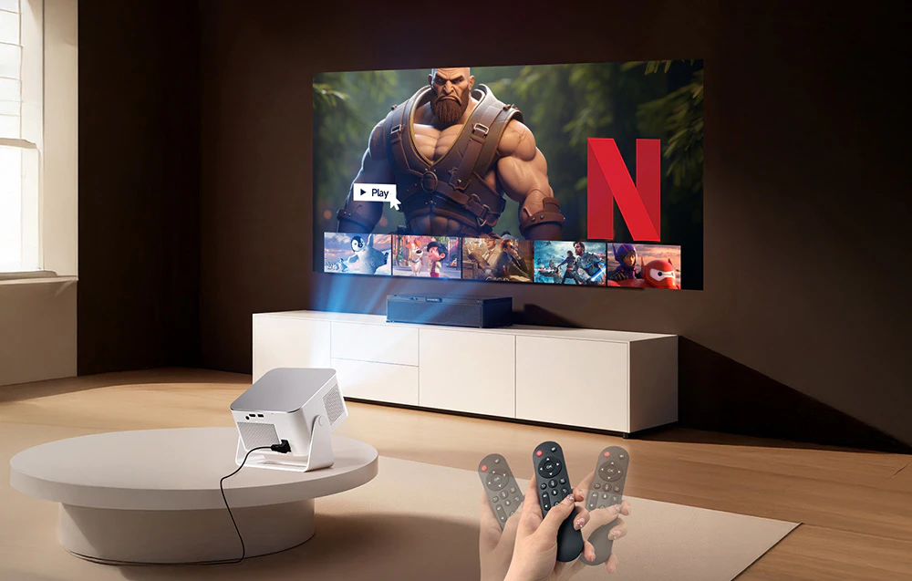 Un proiector alb așezat pe o masă, care afișează meniul Netflix pe perete, și o mână care ține telecomanda