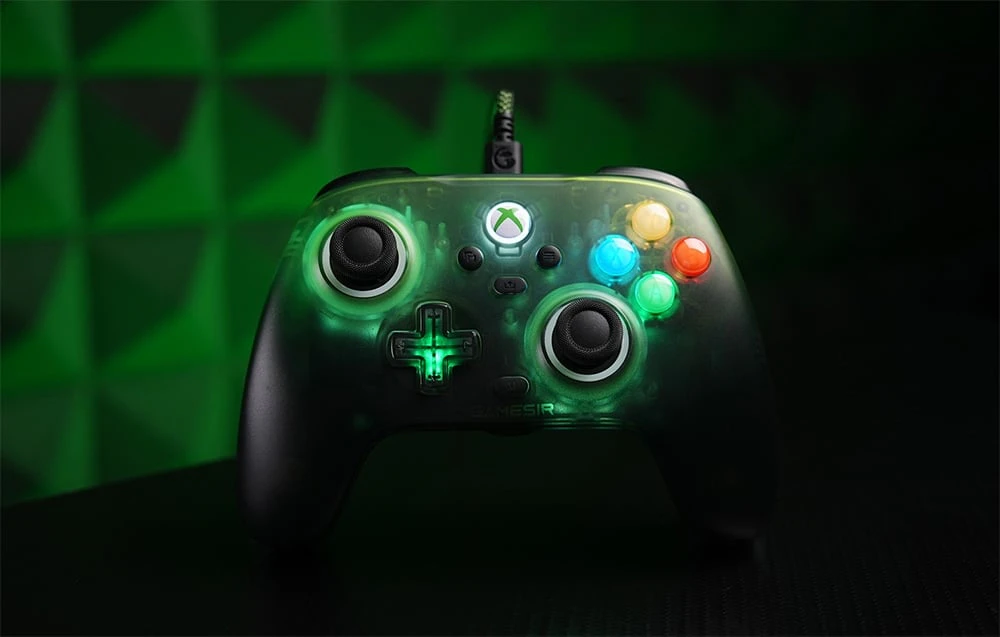 Controler de joc cu fir, cu carcasă translucidă și butoane retroiluminate pe un fundal verde închis
