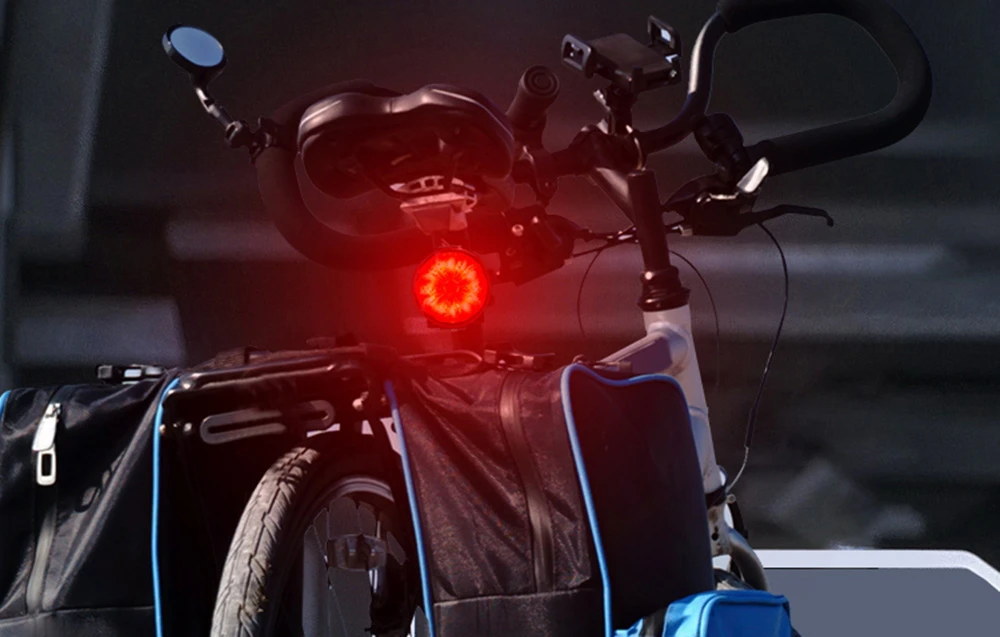 Bicicletă cu genți și lumină rotundă roșie de bicicletă pe fundal întunecat