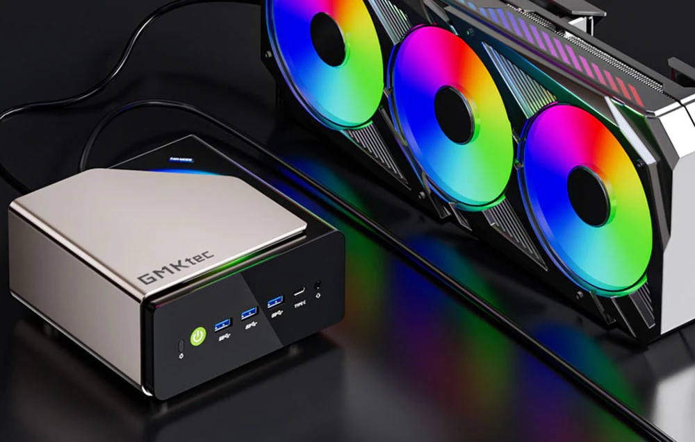Mini PC GMKtec este așezat pe o masă neagră. Alături de 3 ventilatoare colorate.