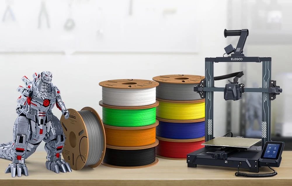 imprimantă 3D, bobine de filament în diverse culori și un model de dinozaur robotic pe birou