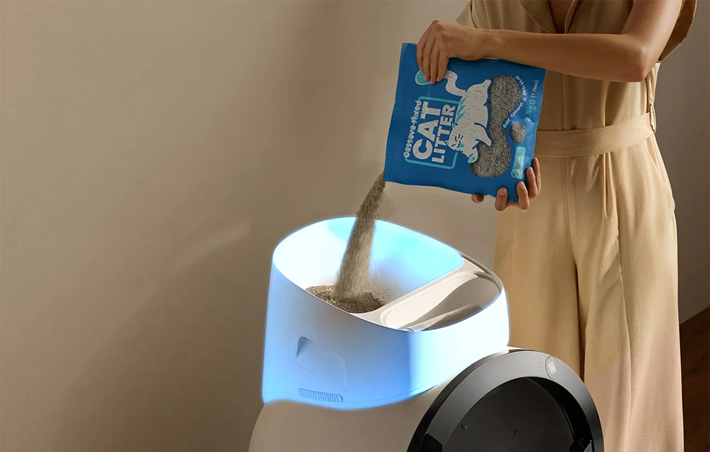 O femeie care adaugă nisip în rezervorul alb al unei cutii de nisip automate