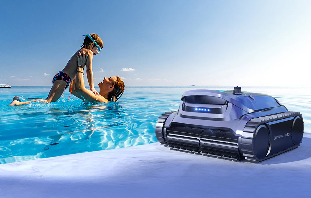 Mamă și copil în piscină lângă robotul de piscină Wybot de pe mal
