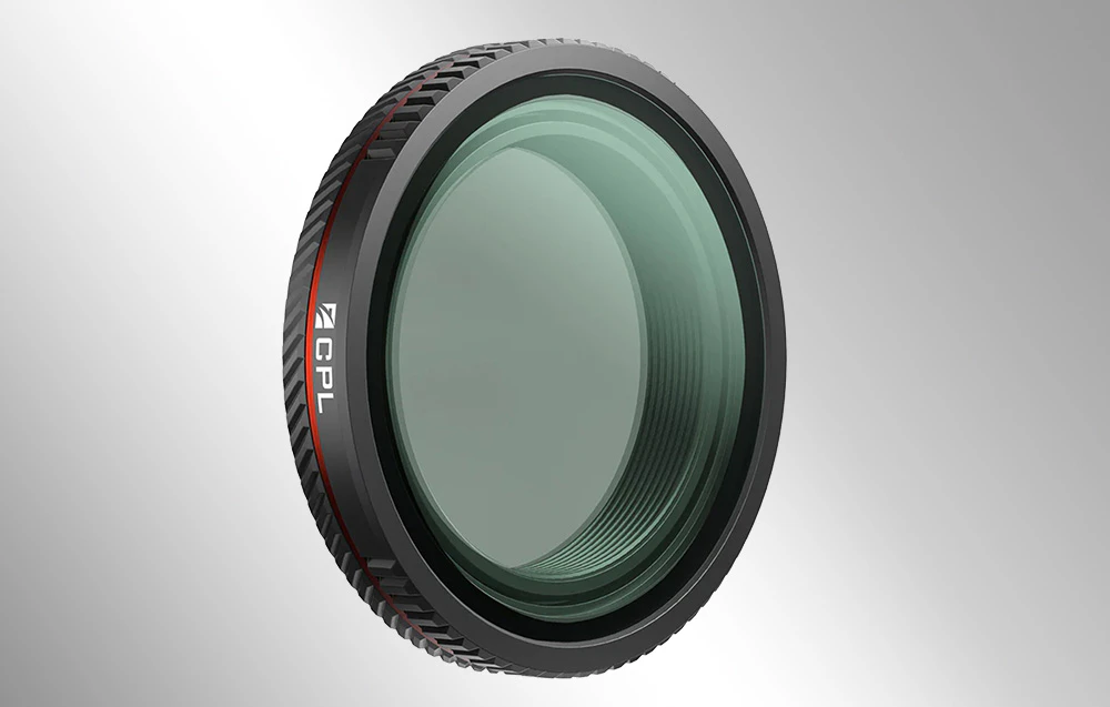 Filtru fotografic negru cu sticlă verzui și inscripția „CPL” pe carcasă, pe un fundal gri.