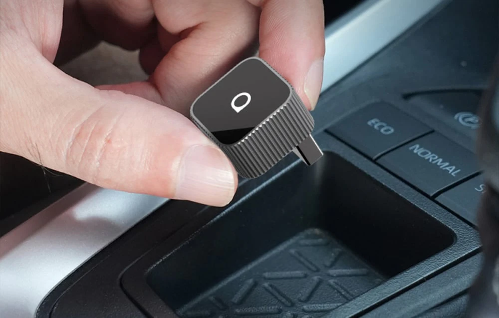 O mână care conectează un adaptor la CarPlay și Android Auto într-o mașină