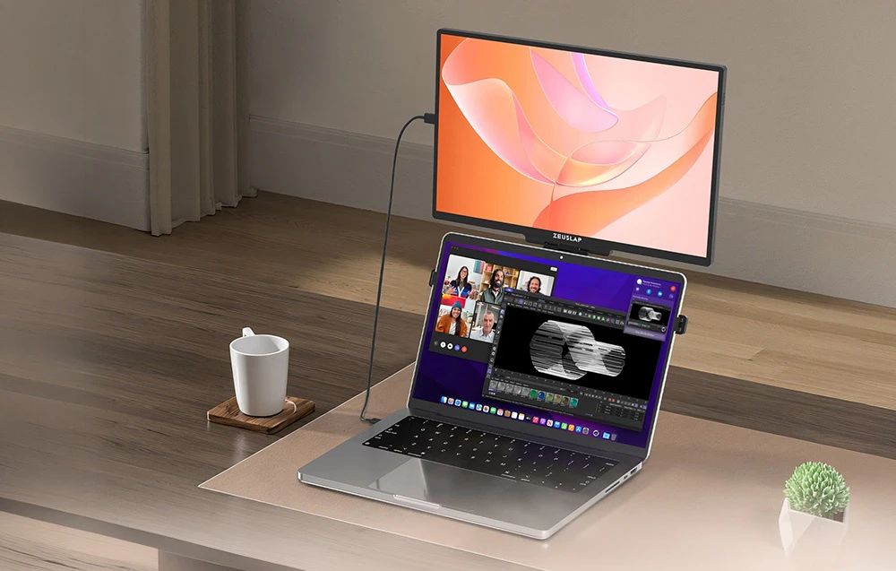 Monitor portabil ZEUSLAP montat deasupra ecranului unui laptop pe un birou, afișând grafică abstractă