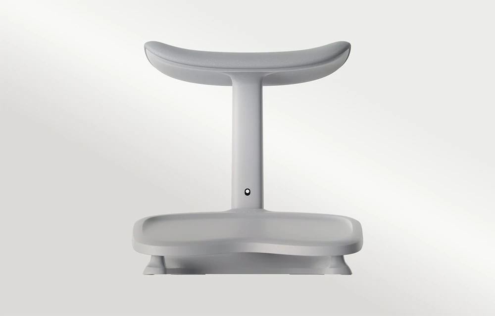 Un suport pentru picioare de birou gri, cu formă ergonomică și un suport curbat pentru picioare, pe un fundal deschis, de culoare uniformă