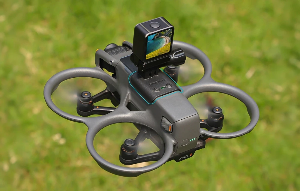 Vedere de sus a dronei zburând deasupra ierbii, cu un adaptor universal și o mică cameră de acțiune pe corp.