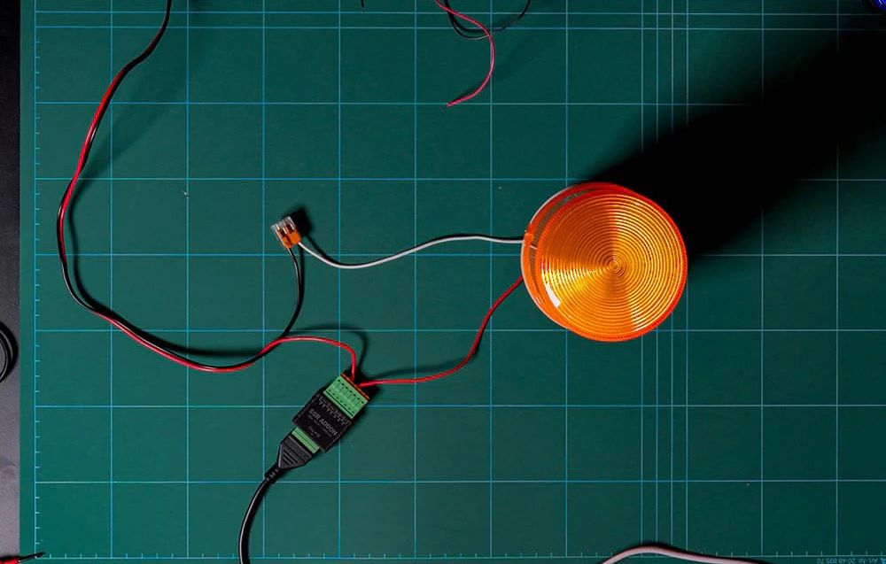 O lumină de avertizare portocalie conectată prin fire la modulul ADDON SSR și un conector Wago pe un covoraș verde