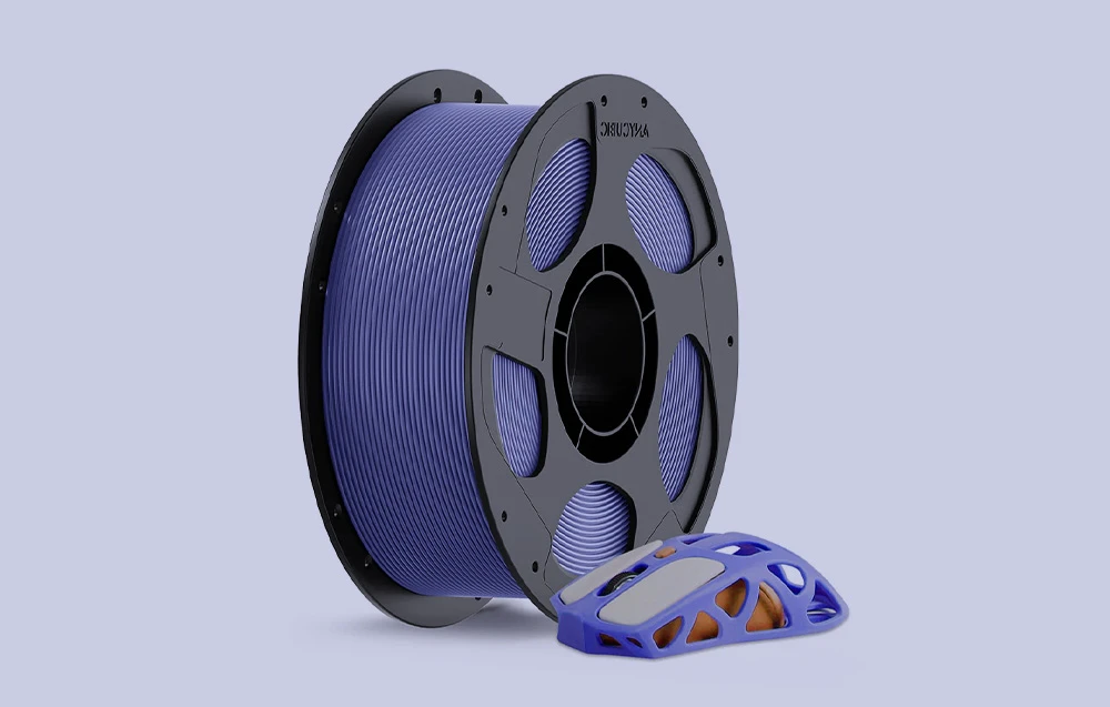 Filament de culoare violet, lângă el se află un mouse de computer realizat prin imprimare 3D.