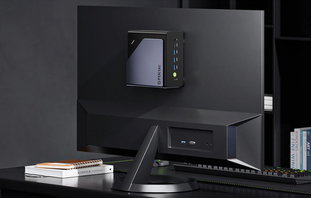 Mini PC GMKtec montat pe spatele unui monitor într-un birou modern negru
