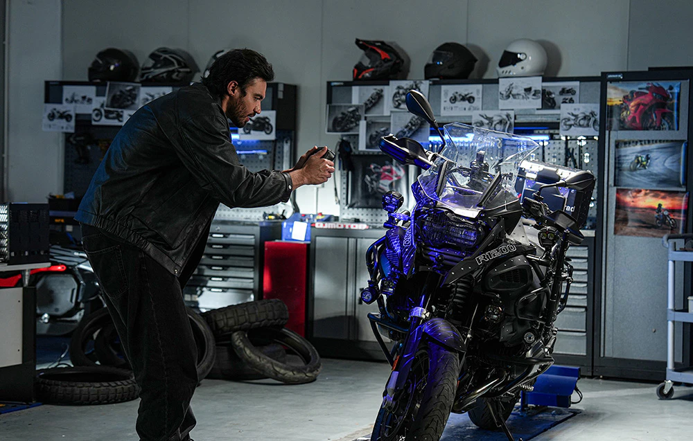 Un bărbat într-un atelier de motociclete scanează partea frontală a unei motociclete cu un scaner portabil