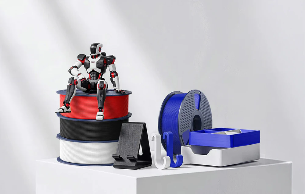 O figurină de robot așezată pe bobine de țesătură lângă recipiente și mânere albe și albastre.