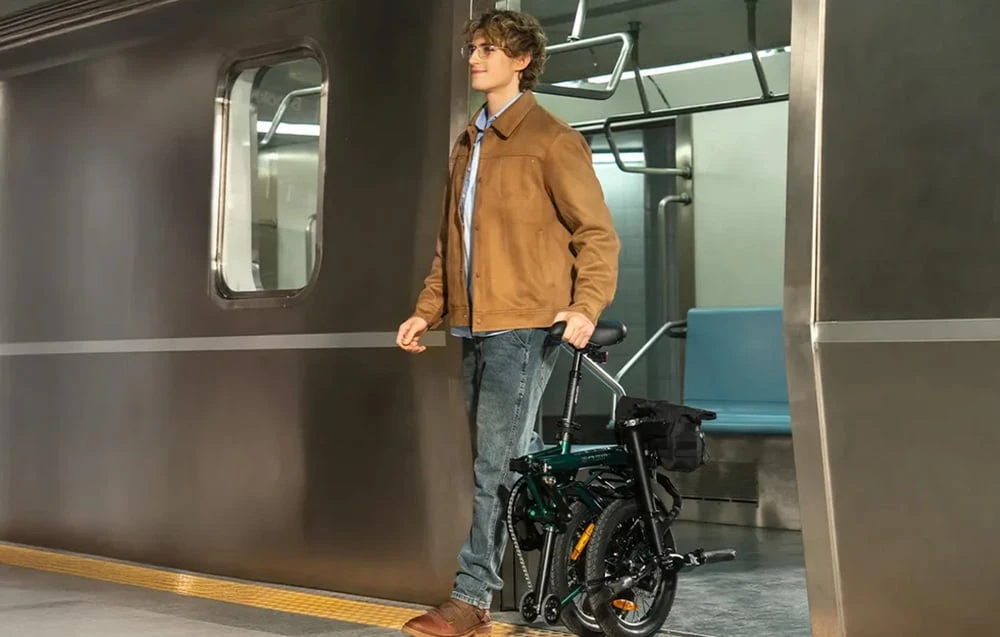 Un bărbat împinge o bicicletă electrică pliabilă pe peronul metroului