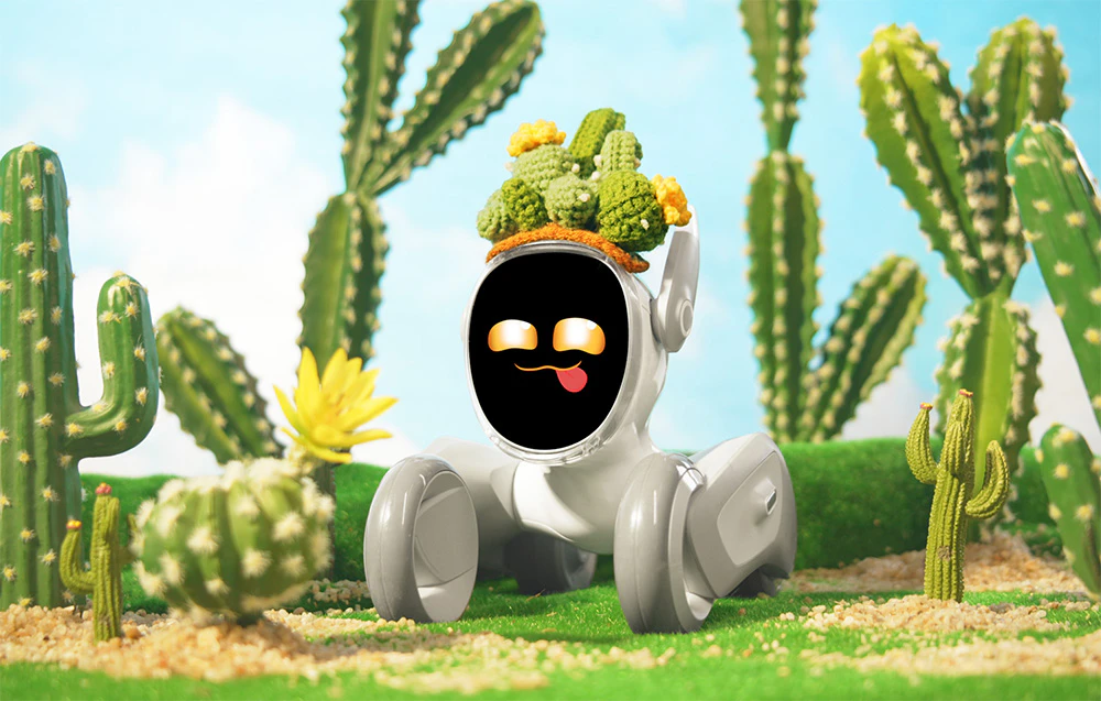 Robotul interactiv Loona într-un costum de cactus pe iarbă verde, înconjurat de cactuși