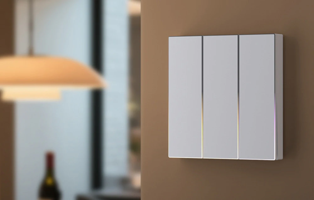Comutator tactil triplu alb cu iluminare fină montat pe un perete bej în interior