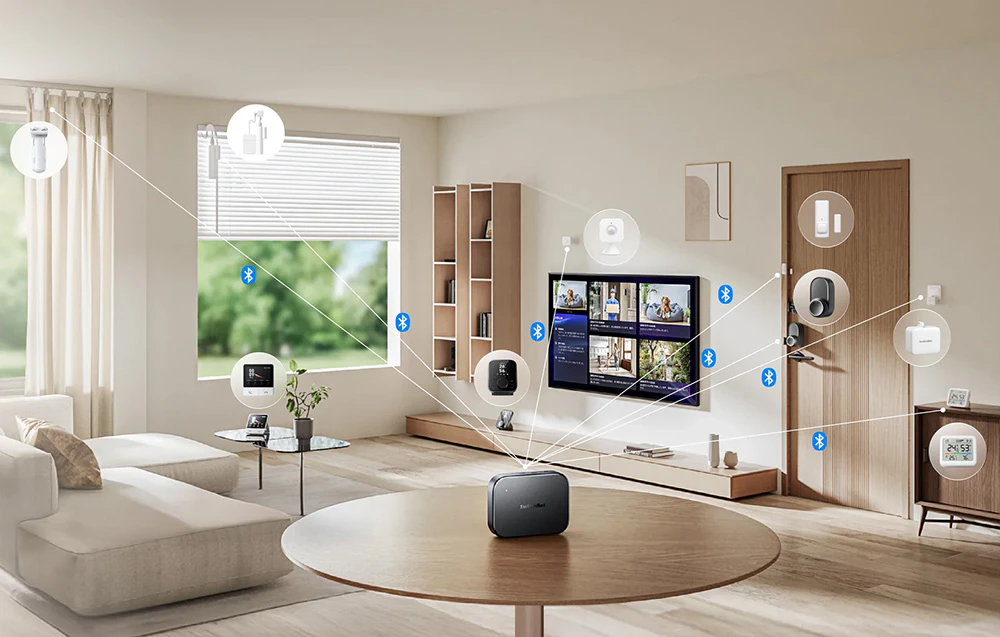 Un living cu un televizor și diverse dispozitive inteligente pentru casă conectate grafic la SwitchBot Gateway așezat pe masă.