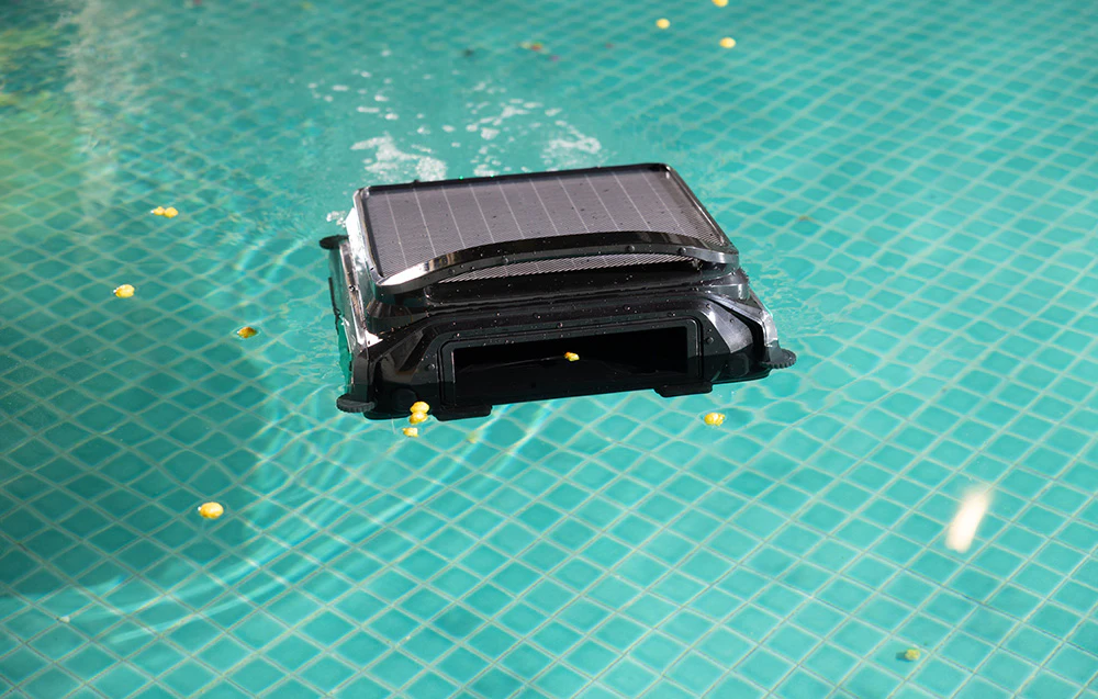 Robotul Wybot F1 curățând piscina cu frunze pe fundul acesteia, printre resturi