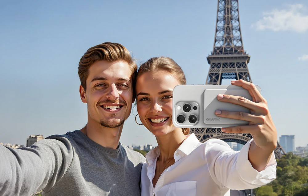 Un cuplu care își face un selfie în fața Turnului Eiffel folosind un smartphone cu o baterie externă magnetică FlexTail.