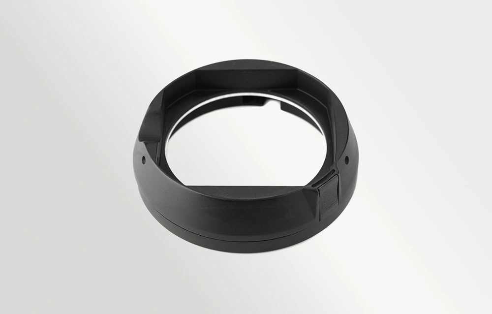 Adaptor de obiectiv negru, în formă de inel, cu montură vizibilă și o gaură în centru, prezentat pe un fundal alb