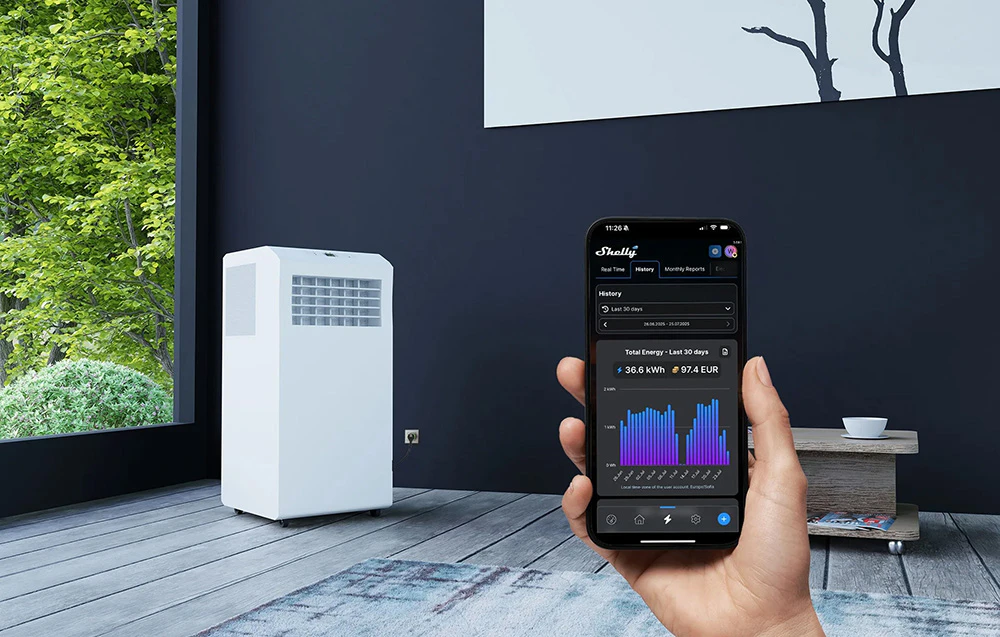 O persoană ținând un smartphone cu aplicația Shelly deschisă, afișând grafice de consum de energie (36,6 kWh), cu un aparat de aer condiționat portabil alb în fundal.