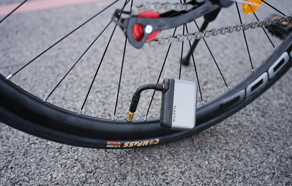 O pompă miniaturală Flextail argintie conectată la supapa roții din spate a unei biciclete de șosea