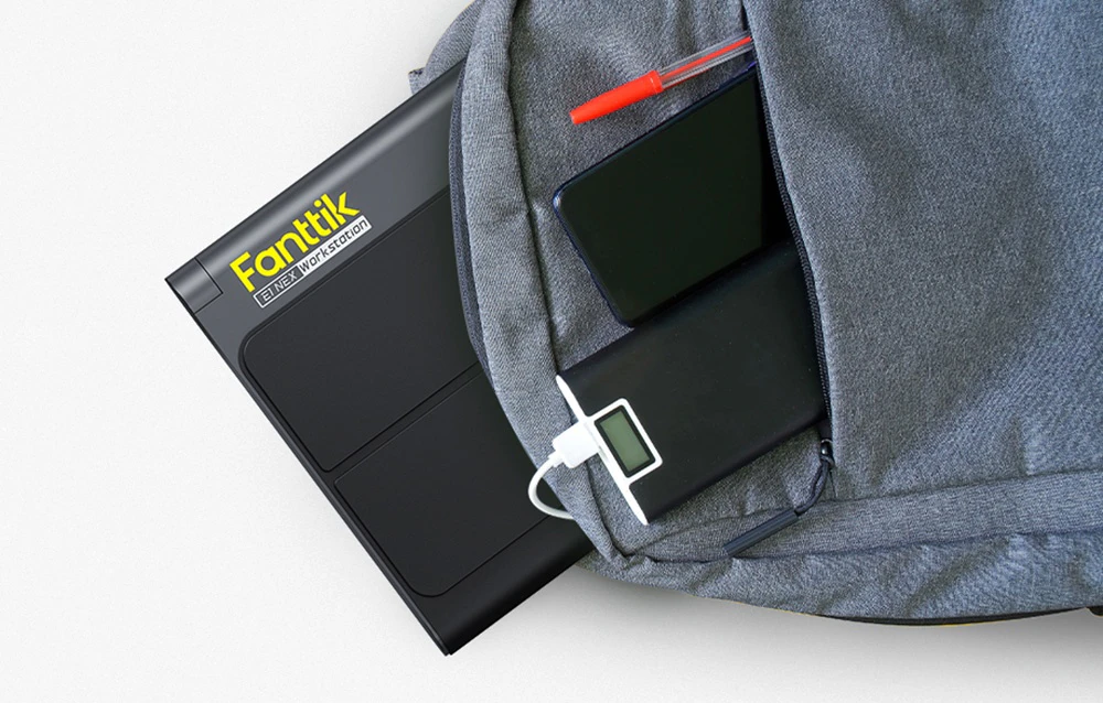 O trusă compactă de scule pentru electronice, parțial ascunsă într-un rucsac lângă o baterie externă și un portofel.