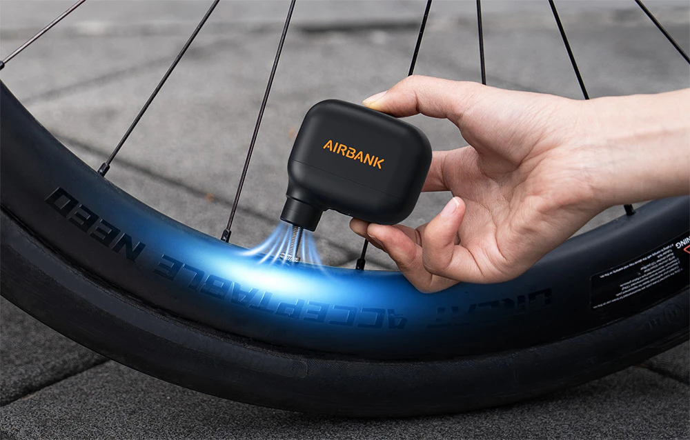 Pompa mini Airbank atașată la o supapă de bicicletă în timp ce umflă o anvelopă în aer liber.
