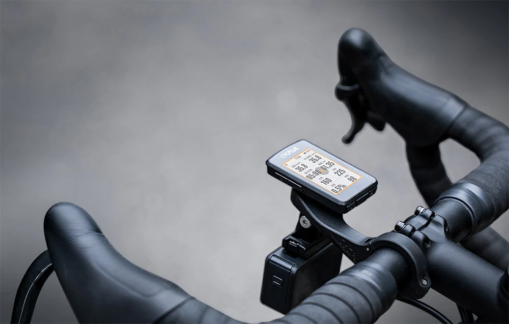 Computerul de bicicletă Cycplus montat pe un suport de ghidon pentru bicicletă de șosea, cu suportul pentru cameră vizibil sub acesta