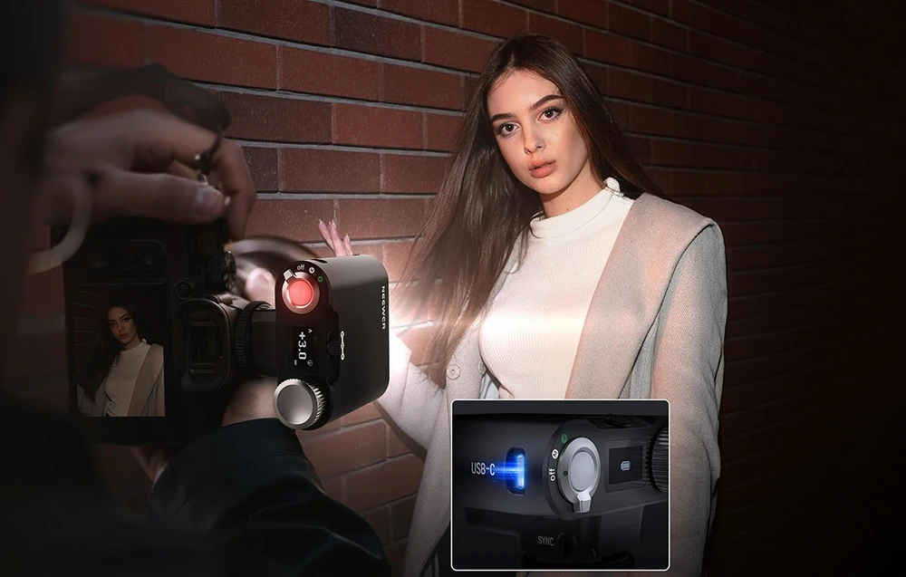 Un fotograf face o fotografie unei femei care stă lângă un zid de cărămidă, folosind iluminare laterală suplimentară.