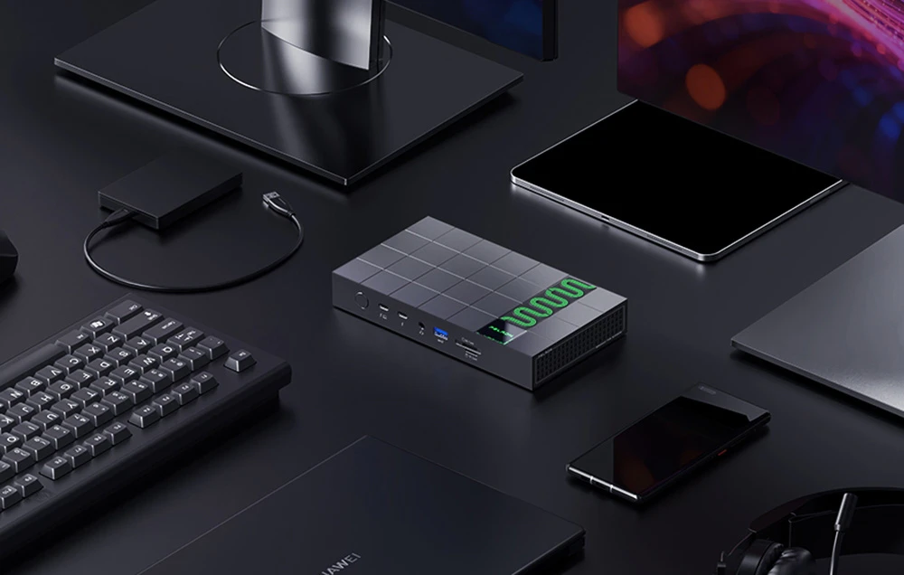 Stația de andocare multi-port Peladn poziționată central pe un birou de computer de culoare închisă, înconjurată de periferice precum o tastatură, un mouse, un smartphone, un hard disk extern și un suport pentru monitor.