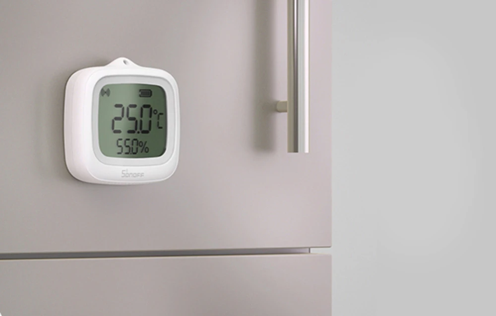 termometru-higrometru digital alb care arată 29,0°C și 55,0% umiditate montat pe suprafața unui frigider