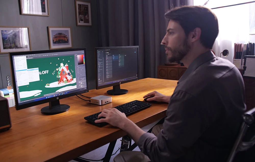 Un bărbat care lucrează la un computer cu 2 monitoare, folosind un program de grafică