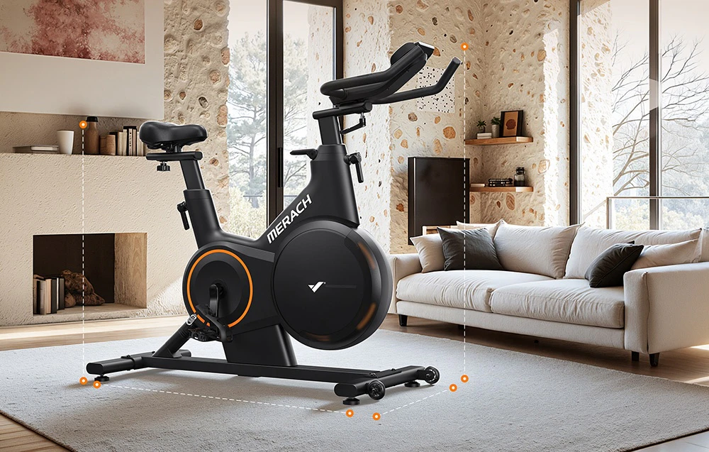 O bicicletă de exerciții Merach neagră, cu accente portocalii, amplasată pe un covor într-un living luminos