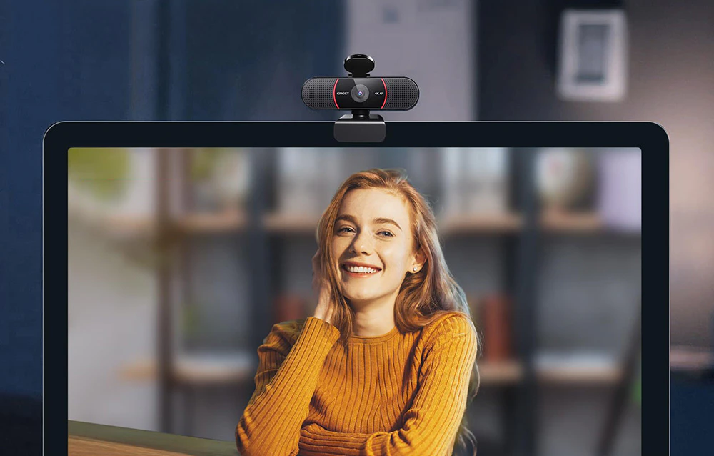 O femeie zâmbitoare vizibilă pe ecranul monitorului în timpul unui apel prin camera web.