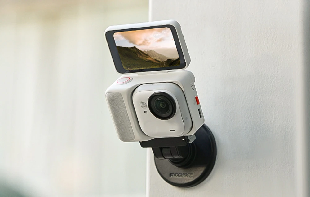 Cameră Insta360 GO 3 albă cu ecran ridicat, montată magnetic pe un stativ alb.