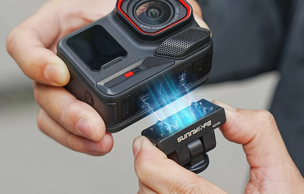 Mâini care țin camera neagră și suportul Sunnylife cu eliberare rapidă fiind aduse mai aproape de aceasta, prezentând o imagine cu atașarea magnetică.