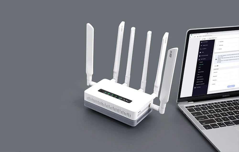 Un router alb cu șase antene verticale se află pe un fundal gri lângă un laptop deschis care afișează panoul de administrare